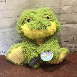 Green plush frog toy with yellow accents sitting on a table