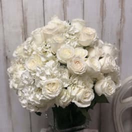 White roses and hydrangeas arranged in a square glass vase
