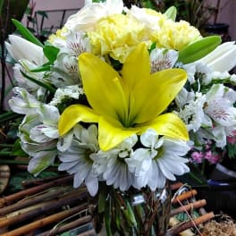 Yellow lily bouquet with white daisies in a glass vase