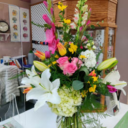 Tall mixed bouquet with lilies, roses, hydrangea, and snapdragons in a glass vase