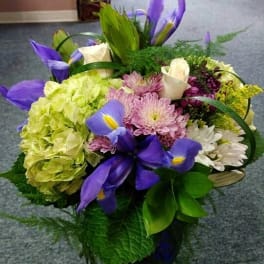 Bouquet of purple irises, hydrangeas, and mixed blooms in a basket
