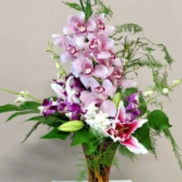 Tall bouquet of pink and purple orchids in a glass vase