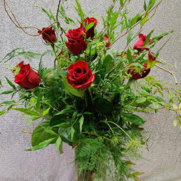 Red roses in a clear glass vase with airy greenery