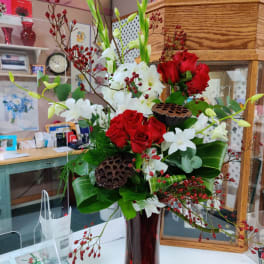Red and white floral arrangement in a tall red vase