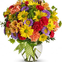 Colorful mixed bouquet in a clear glass vase with a green polka-dot ribbon