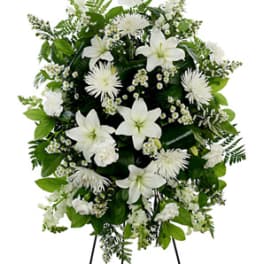 White floral standing spray on an easel with lilies and chrysanthemums