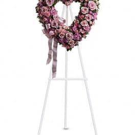 Heart-shaped pink rose wreath on a white easel with ribbon