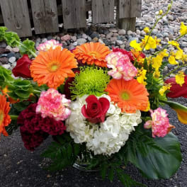 Mixed bouquet with orange gerbera daisies, red roses, white hydrangea, and yellow orchids