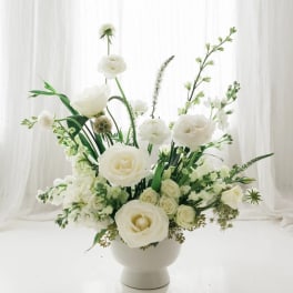 White floral arrangement in a white pedestal vase