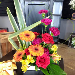 Bright mixed bouquet with roses, gerbera daisies, carnations, and alstroemeria in a white container