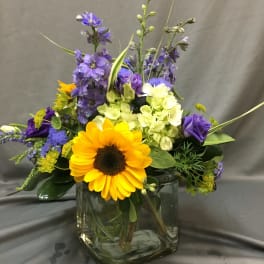 Mixed bouquet with a sunflower and purple blooms in a glass vase
