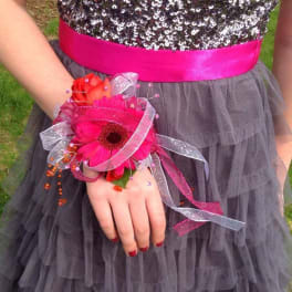 Pink floral wrist corsage with ribbon on a person’s hand
