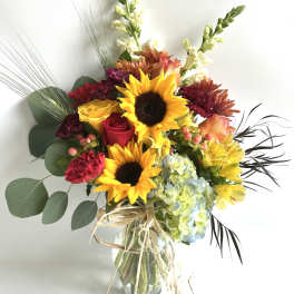 Bouquet of sunflowers, roses, hydrangea, and mixed blooms in a glass vase