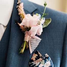Pink boutonniere pinned to a blue suit jacket