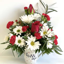 Red roses and white daisies in a white mug vase