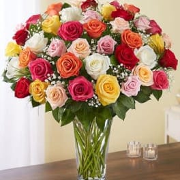 Mixed roses in many colors arranged in a clear glass vase