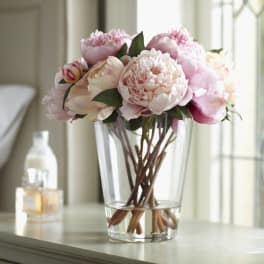 Pink and white peonies in a clear glass vase