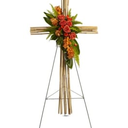 Standing floral cross with red roses and orange accents on a metal easel
