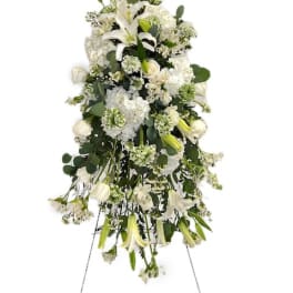White funeral spray with lilies and roses on a standing easel