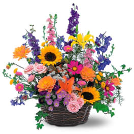 Mixed bouquet in a dark woven basket with sunflowers, lilies, and daisies