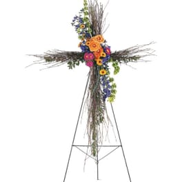 Standing floral cross with orange, blue, and pink flowers on a metal easel