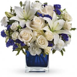 White roses and lilies arranged in a blue glass vase