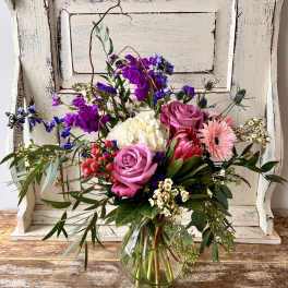 Mixed bouquet in a clear glass vase with pink, purple, white, and blue flowers