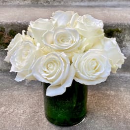White roses arranged in a green glass vase