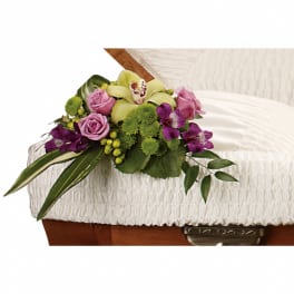 Floral casket spray with pink roses, green mums, and purple orchids