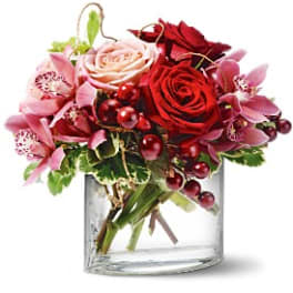 Bouquet of red and pink roses with orchids in a clear glass vase