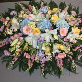 Large pastel floral spray with lilies, hydrangeas, and daisies on dark foliage