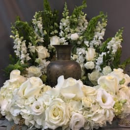 White floral funeral arrangement with a dark urn in the center