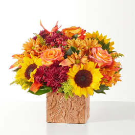 Autumn bouquet with sunflowers, roses, and mums in a leaf-patterned vase
