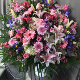 Large mixed bouquet with pink lilies, roses, and purple flowers in a white vase
