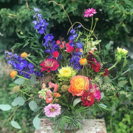 Mixed bouquet with bright blue, pink, orange, and yellow flowers in a vase