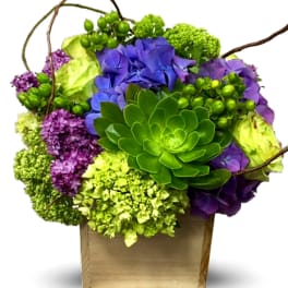 Purple and green floral arrangement in a wooden box