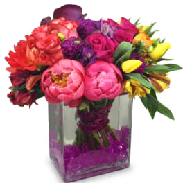 Colorful bouquet of mixed flowers in a square glass vase