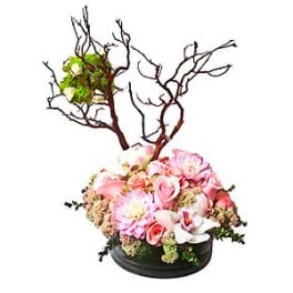 Pink floral arrangement with branches in a low black container