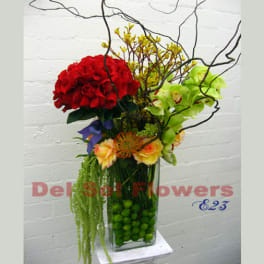 Tall floral arrangement with red and green blooms in a glass vase