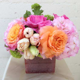 Pink and orange roses with hydrangeas in a square vase