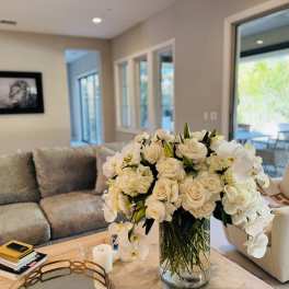 Large white floral arrangement in a clear glass vase on a coffee table