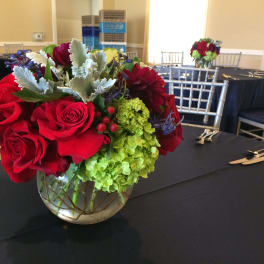 Red roses and green hydrangeas in a glass bowl vase on a table