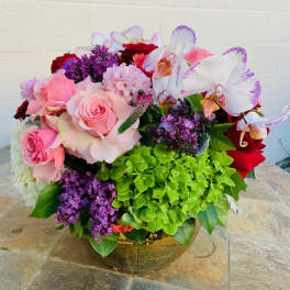 Pink roses and white orchids in a gold vase with purple blooms