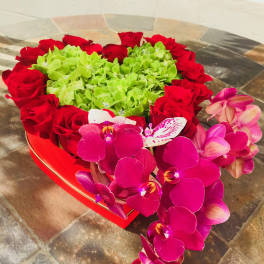 Heart-shaped arrangement of red roses and pink orchids with green hydrangeas