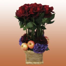 Red roses in a square vase with apples and purple flowers