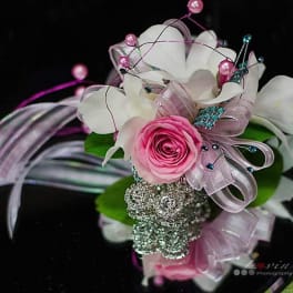 Pink rose corsage with white orchids and ribbon on a black box