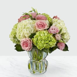 Pink roses and green hydrangeas arranged in a clear glass vase