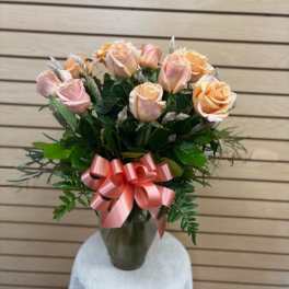 Pink and peach roses in a glass vase with a pink ribbon bow