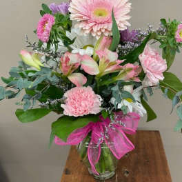 Pink and white mixed bouquet in a glass vase with a pink ribbon