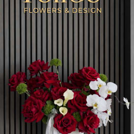 Red roses and white orchids arranged in a white vase